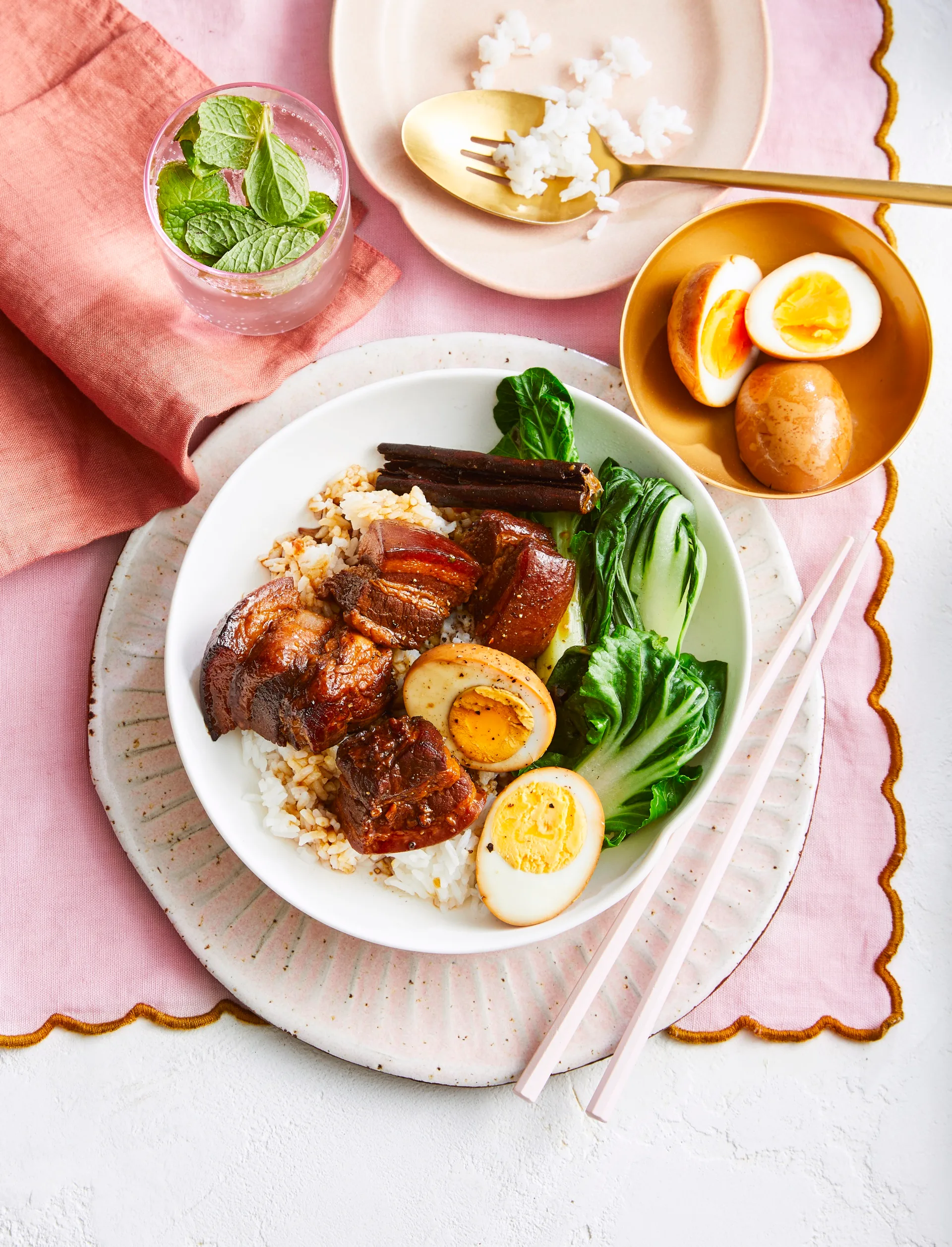 poitrine de porc braisée dans un bol avec œuf dur coupé en deux, légumes verts asiatiques et baguettes sur le côté