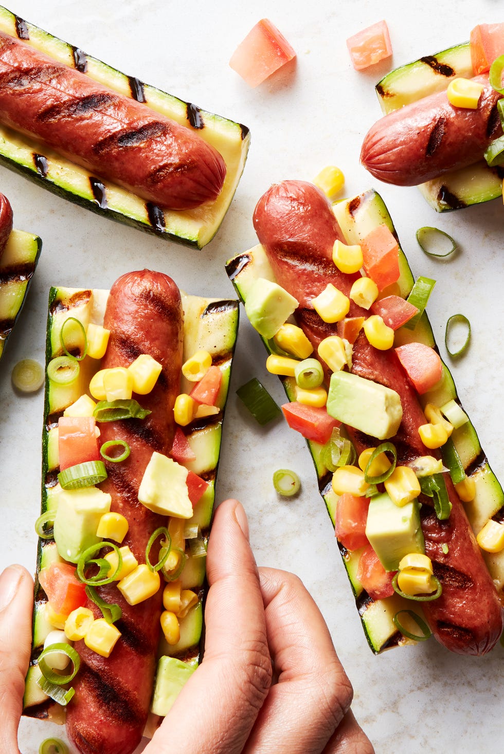 hot-dogs grillés entre des courgettes grillées garnies de salsa d'avocat