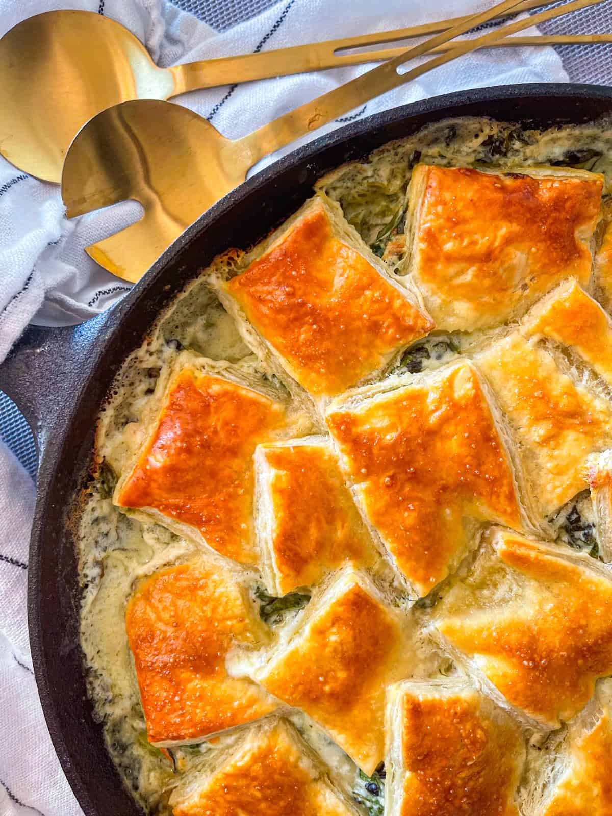 gros plan d'une tarte crémeuse aux épinards et au saumon avec une pâte feuilletée.