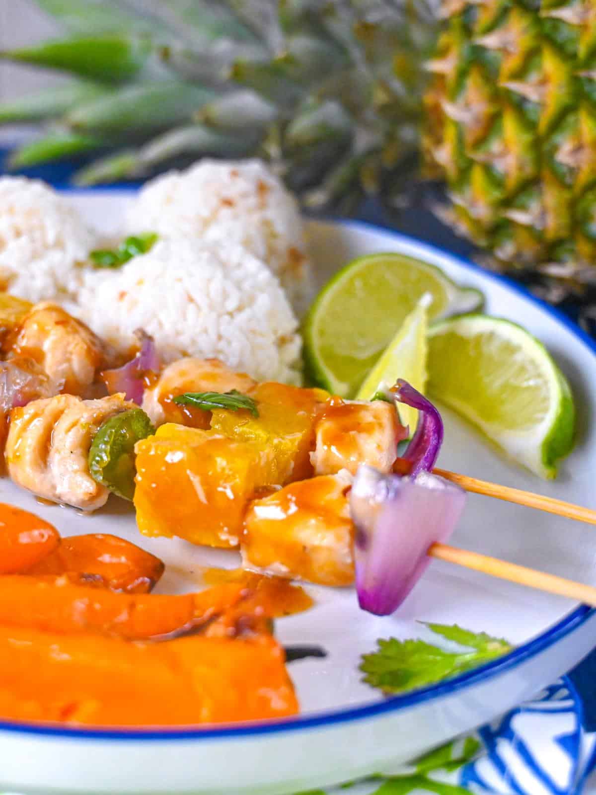 Brochettes de flétan grillées sur une assiette avec riz à la noix de coco et mini poivrons grillés à l'ananas