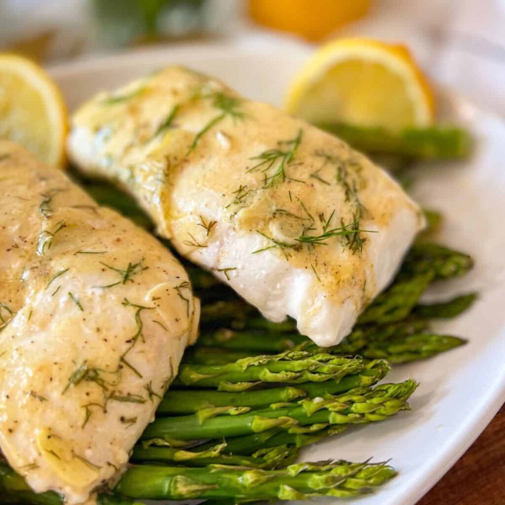 Baked Halibut over asparagus served in a white platter.