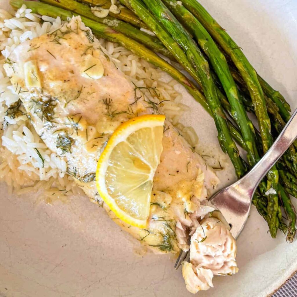 Baked mahi with asparagus and dill sauce in a bowl.