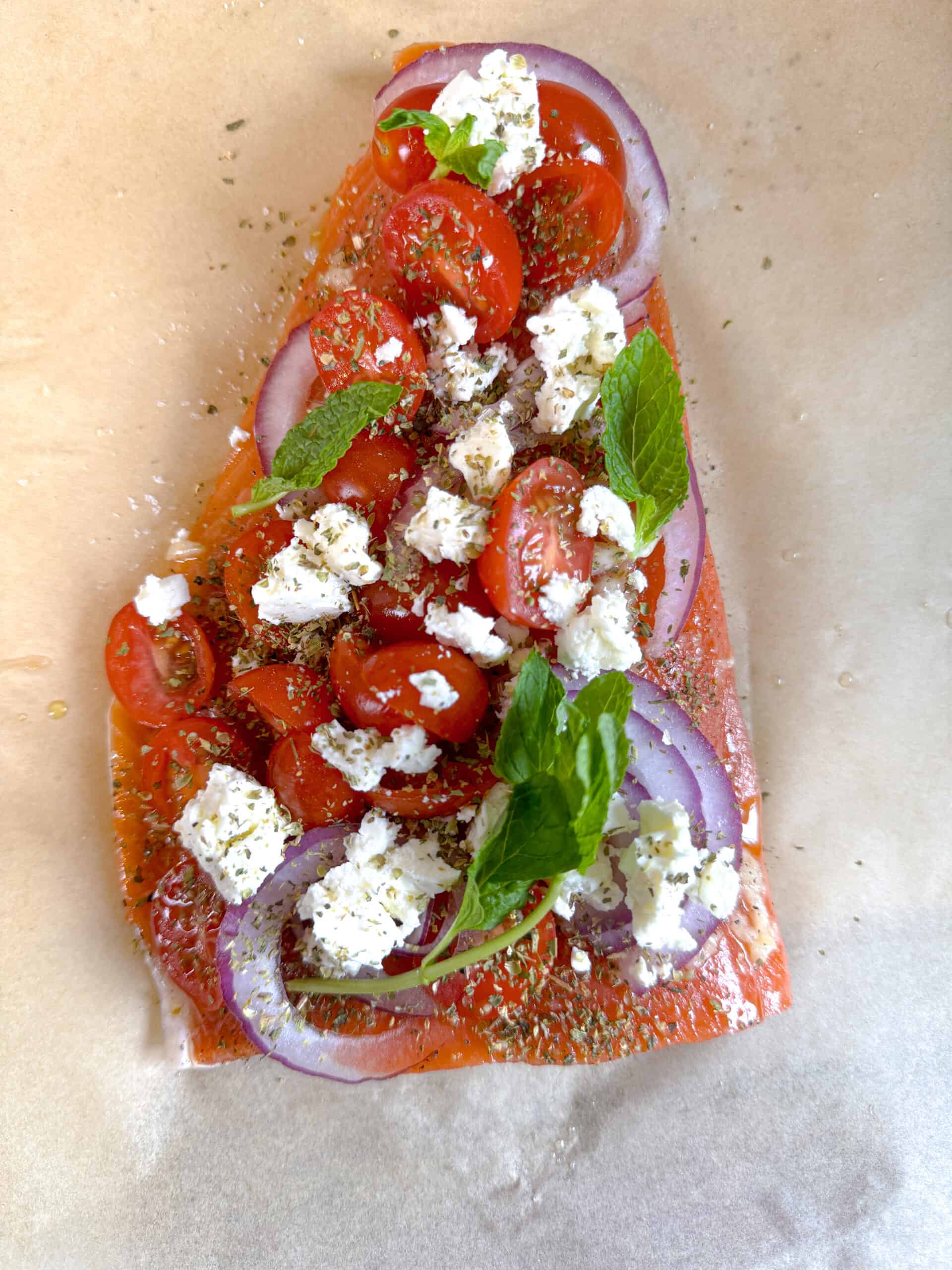 poisson en papillote enveloppé dans du papier sulfurisé avec herbes fraîches, tomates, feta