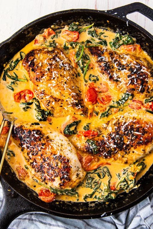 poulet toscan à la crème avec tomates et épinards dans une poêle en fonte noire