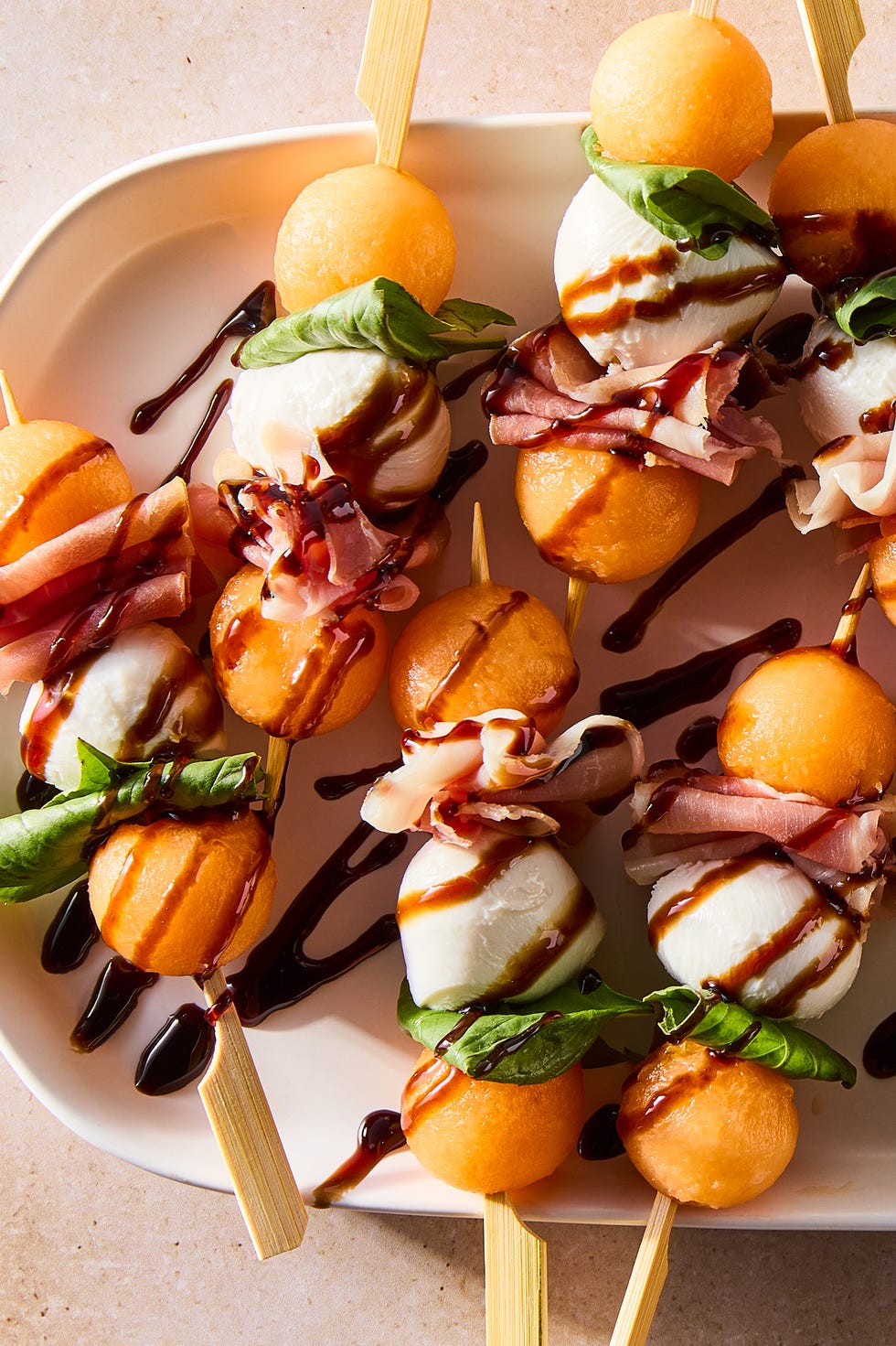 brochettes de boules de cantaloup, boules de mozzarella et feuilles de basilic frais arrosées de glaçage balsamique