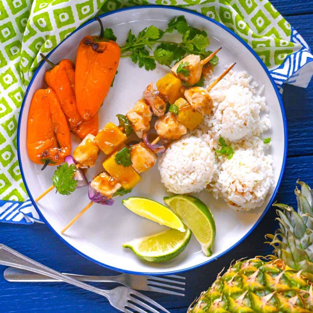 grilled halibut skewers on a plate with coconut rice and grilled mini peppers with pineapple