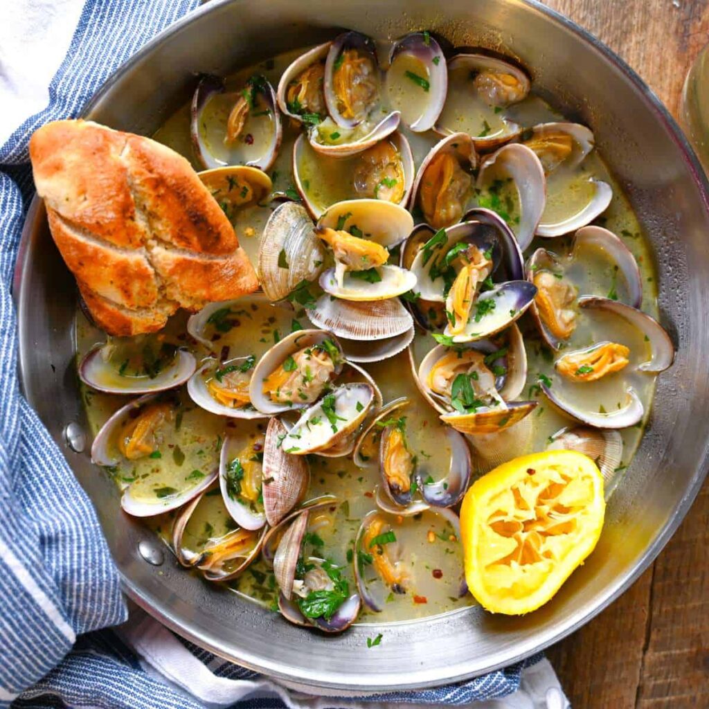 steamed clams in white wine sauce with crusty bread lemon and parsley