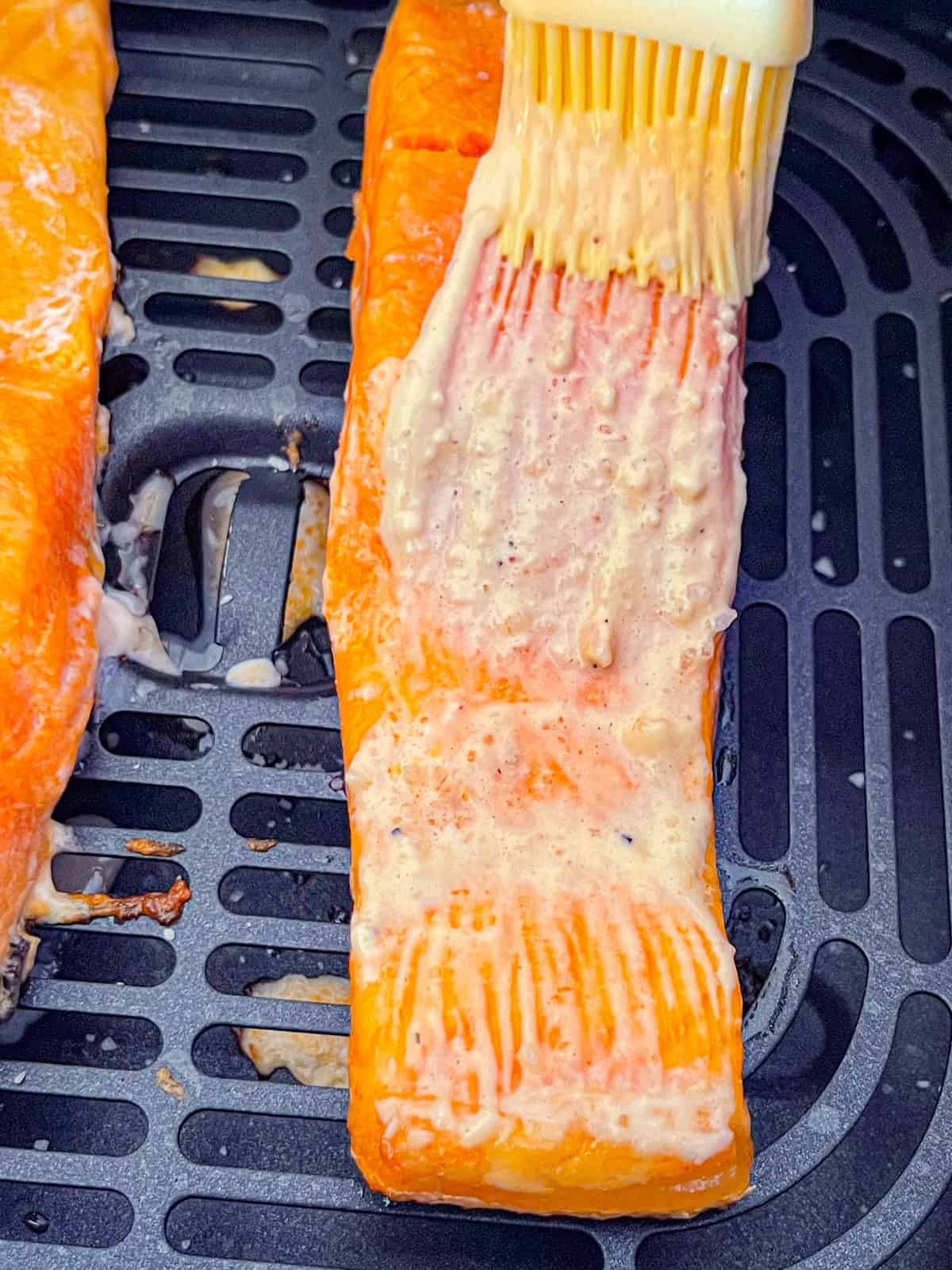 Saumon badigeonné de vinaigrette César dans le panier de la friteuse à air.