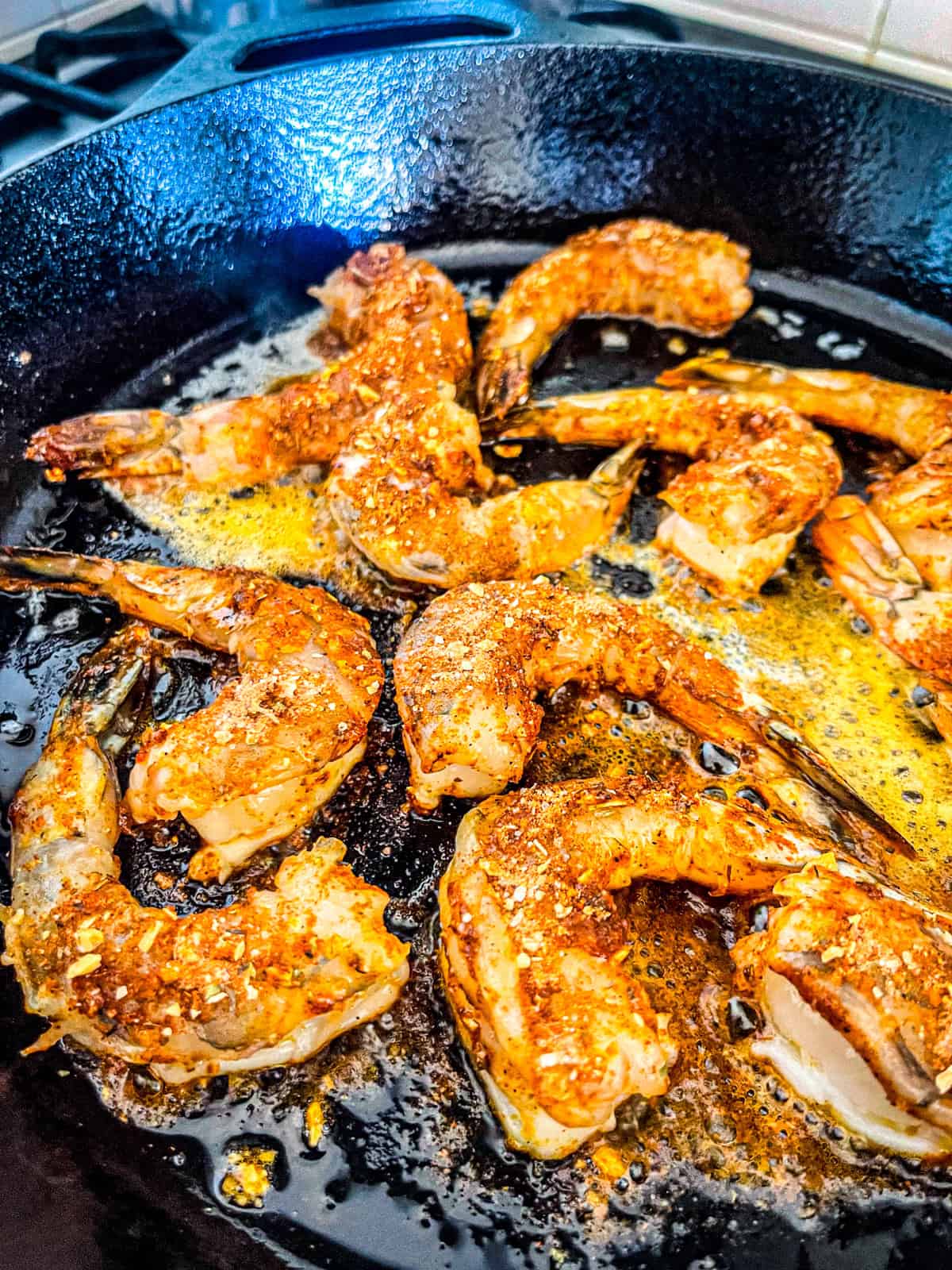 crevettes assaisonnées cuisant dans une poêle noire.