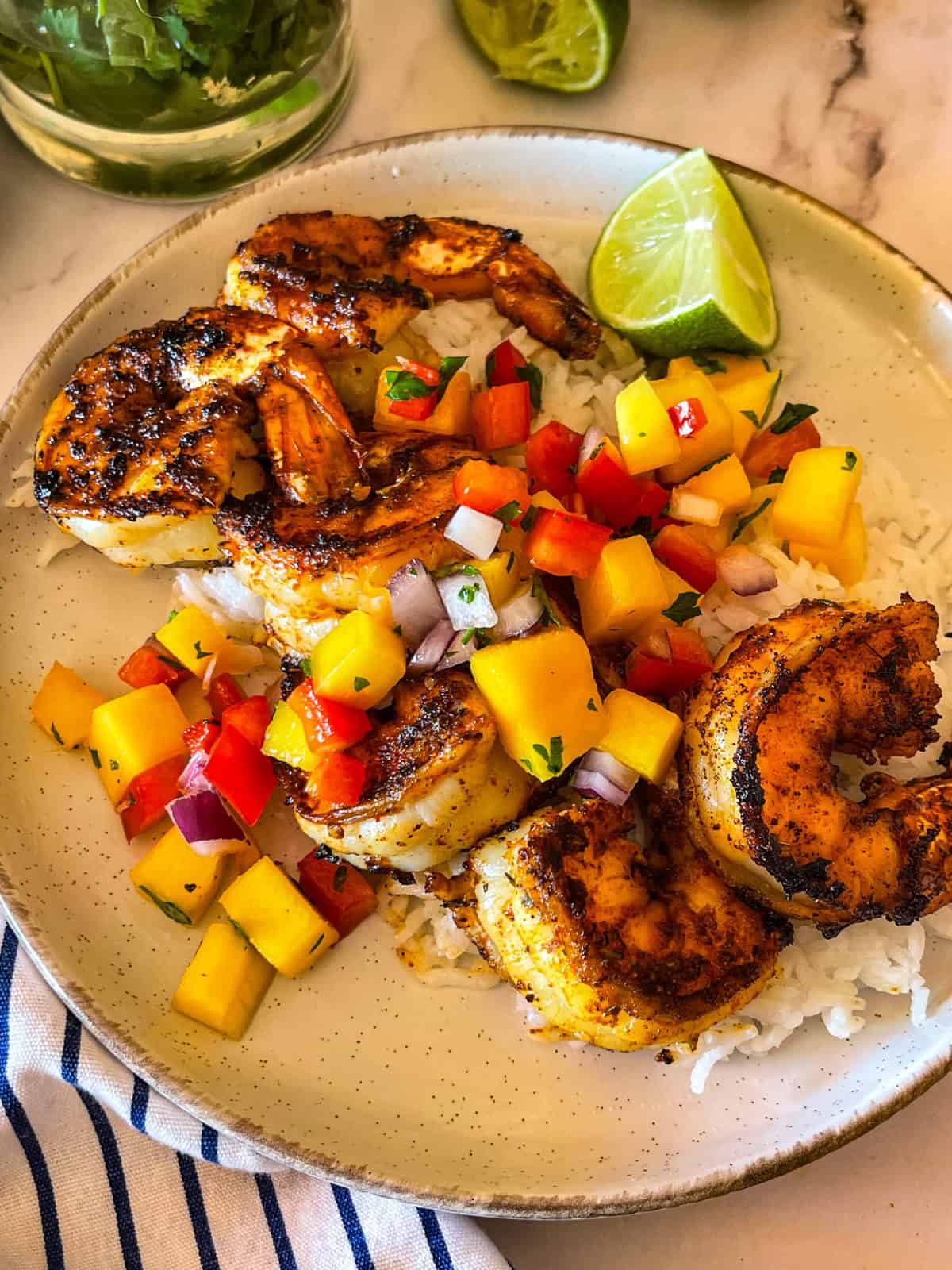 crevettes servies avec salsa à la mangue sur un lit de riz.