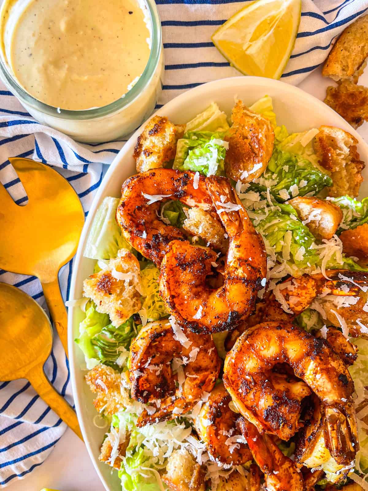 crevettes noircies empilées sur une salade servie sur un plateau.