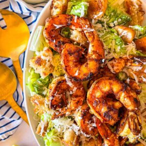 blackened shrimp served over a platter of Caesar salad.