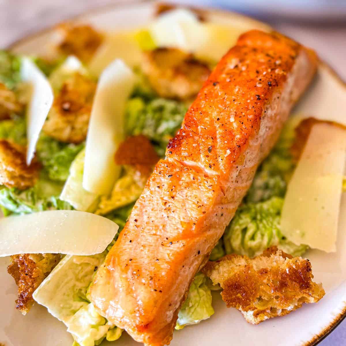 plate of Caesar salad with parmesan, croutons and seared salmon.