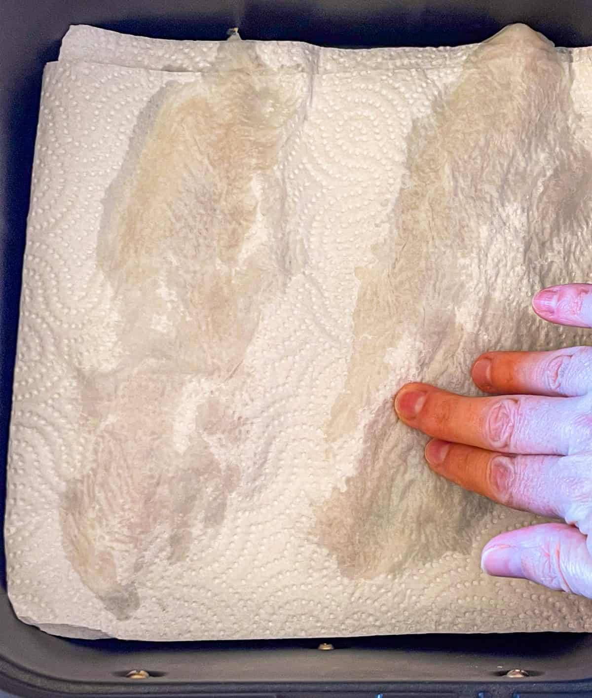 Le poisson décongelé tapoté dans un panier de friteaux à air.