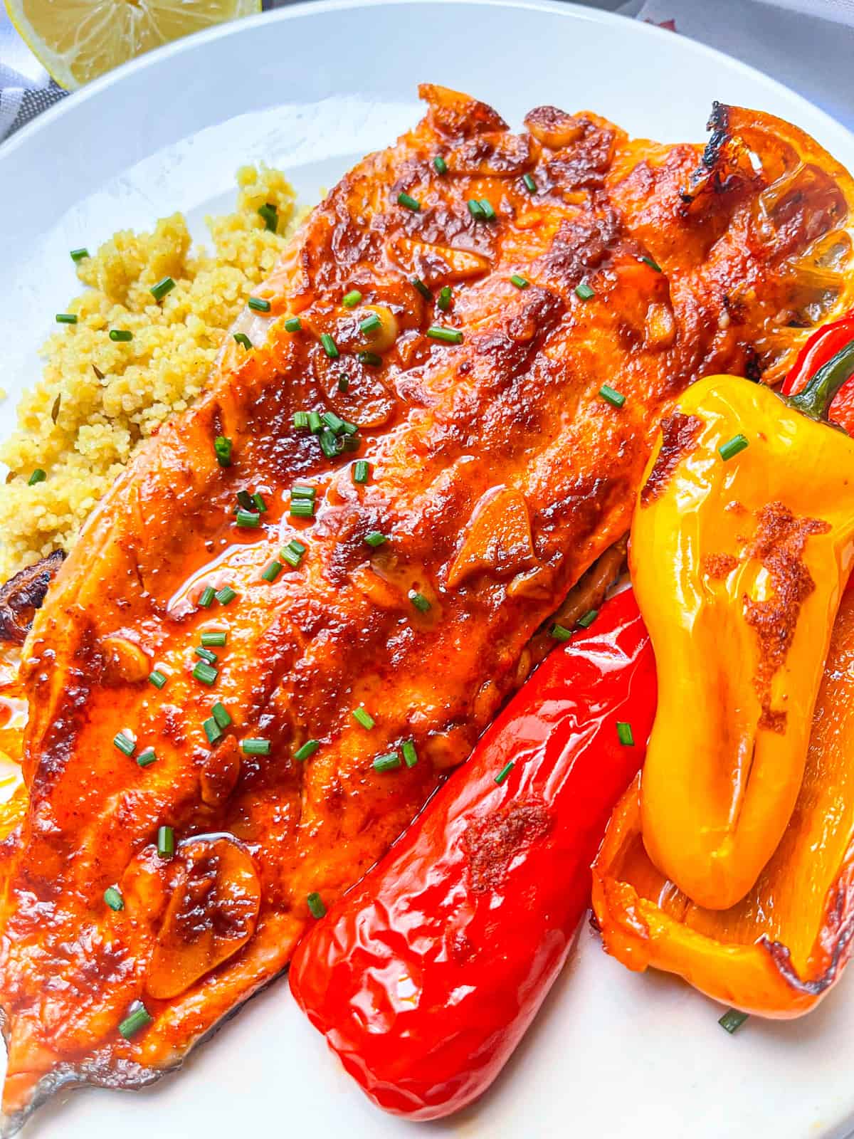 Trout cuit au four vitré avec sauce au beurre paprika sur un lit de couscous et de poivrons multicolores rôtis.