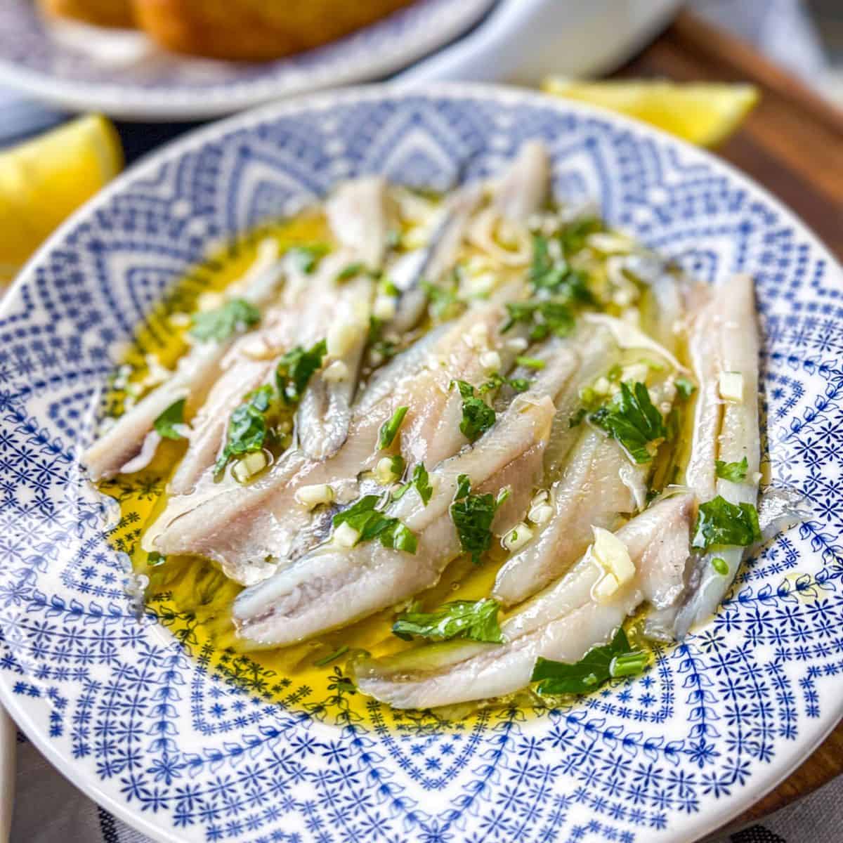 Bocarones on plate with olive oil and herbs.