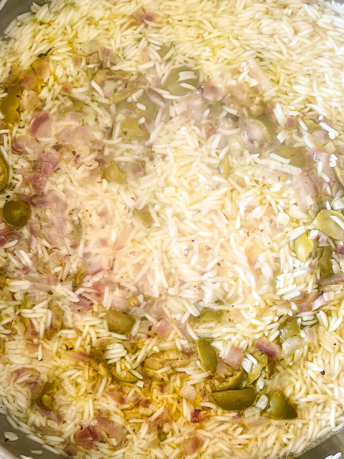 Stocké ajouté au pan avec du riz, des oignons et des olives.