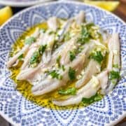 Bocarones sur assiette d'huile d'olive et d'herbes.