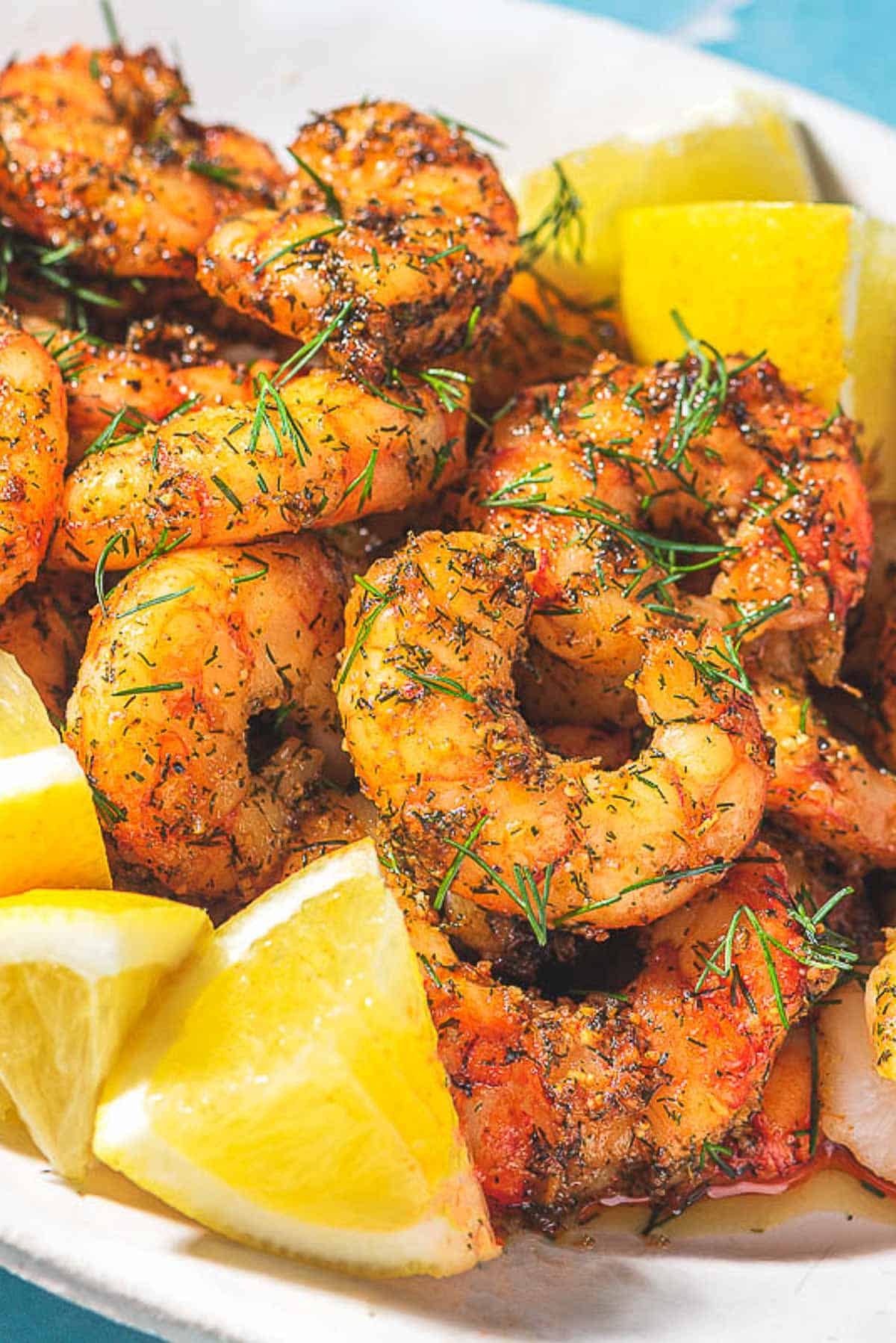 Crevettes de friteuse à air sur un plateau avec des quartiers de citron.