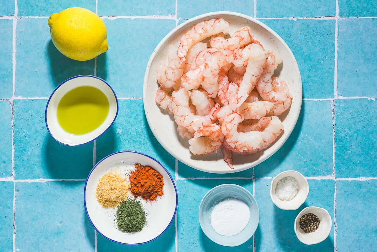 Ingrédients pour les crevettes à la friteuse, y compris les crevettes, le citron, l'huile d'olive, les mauvaises herbes à l'aneth, le paprika, la poudre d'ail, le sel, le poivre noir et le bicarbonate de soude.