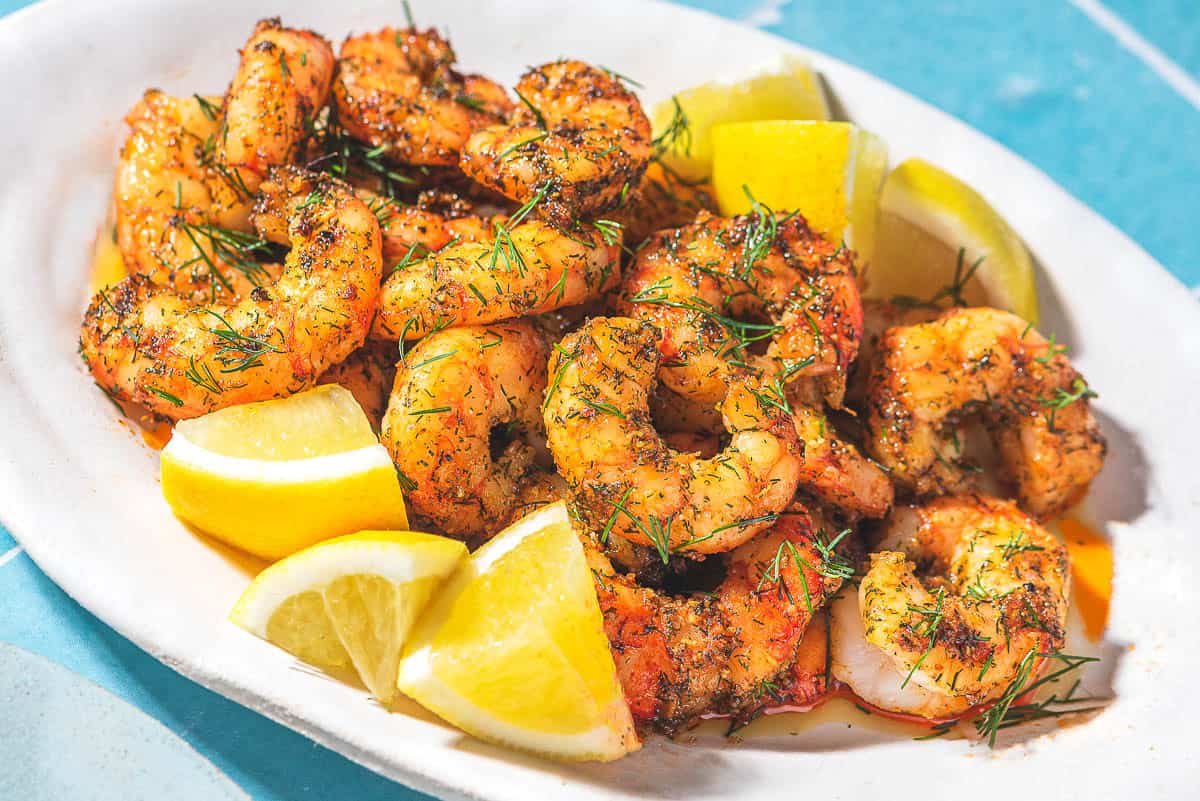 Crevettes de friteuse à air sur un plateau avec des quartiers de citron.