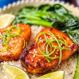 2 pieces of miso se bass on top of a bed of rice and side of greens.