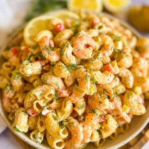 Shrimp pasta salad in a bowl garnished with lemon slices.