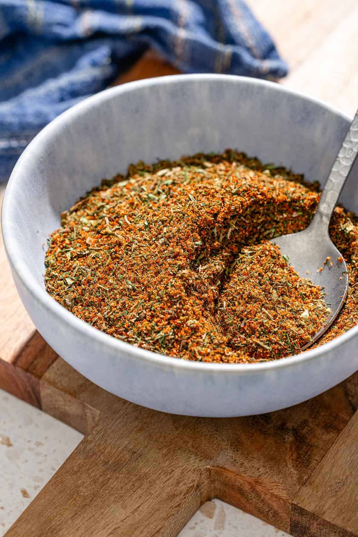 Fish seasoning in a bowl with a spoon on a wooden tray.
