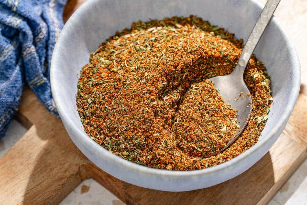 Fish assaisonnant dans un bol avec une cuillère sur un plateau en bois.
