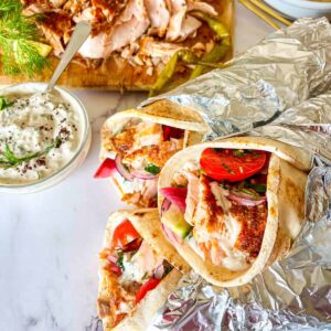 3 Salmon Shawarma wrap over a tray of shawarma.