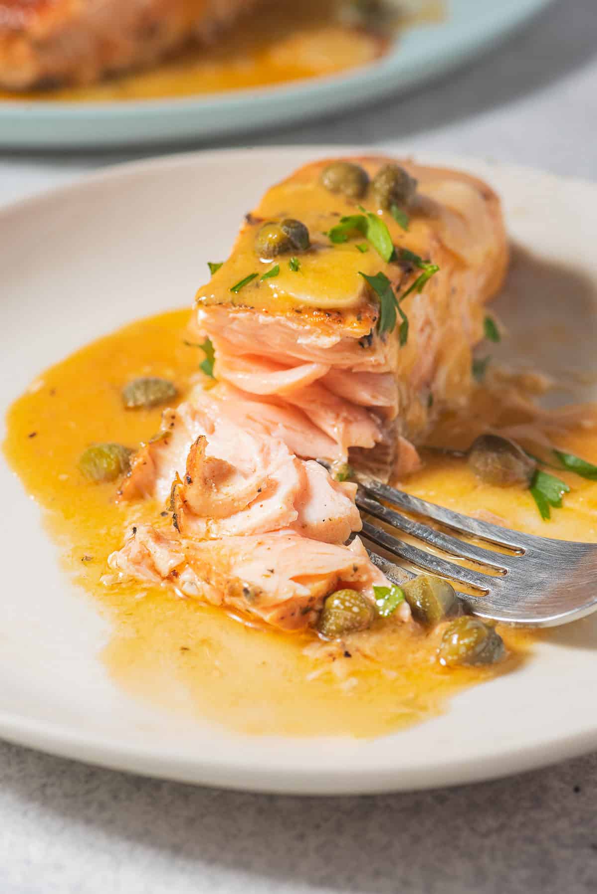 Une fermeture d'un filet de piccata de saumon sur une assiette avec une fourchette.