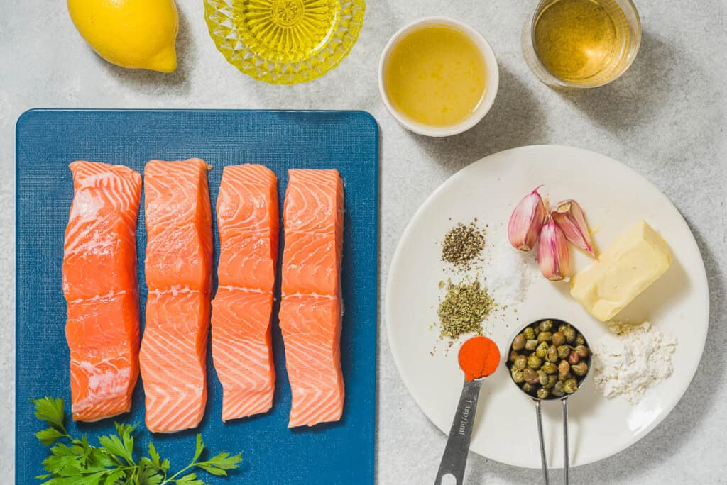 Les ingrédients de Piccata de saumon, y compris le saumon, le paprika sucré, l'origan, le sel, le poivre noir, l'huile d'olive, le beurre, l'ail, la farine, le bouillon de poulet, le vin blanc, le citron, les câpres, le persil et le citron.