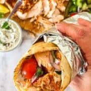 Shawarma Pita enveloppe avec du papier d'aluminium maintenu en main à côté de toute la fixation.