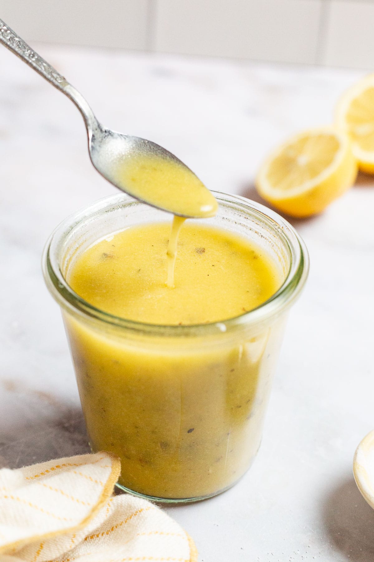 Une cuillerée de vinaigrette au citron étant soulevée d'un pot de vinaigrette de citron.