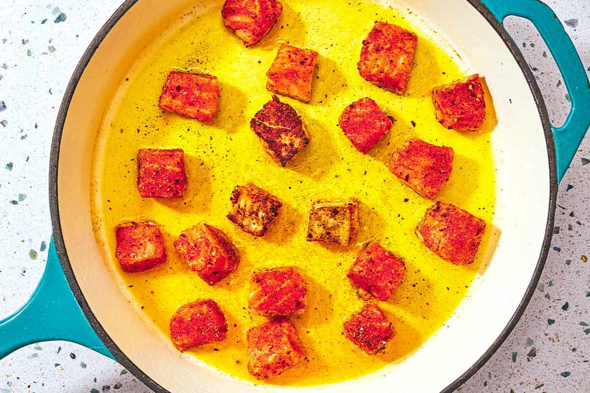 Des morceaux de saumon de la taille d'une bouchée sont saisis dans une poêle.