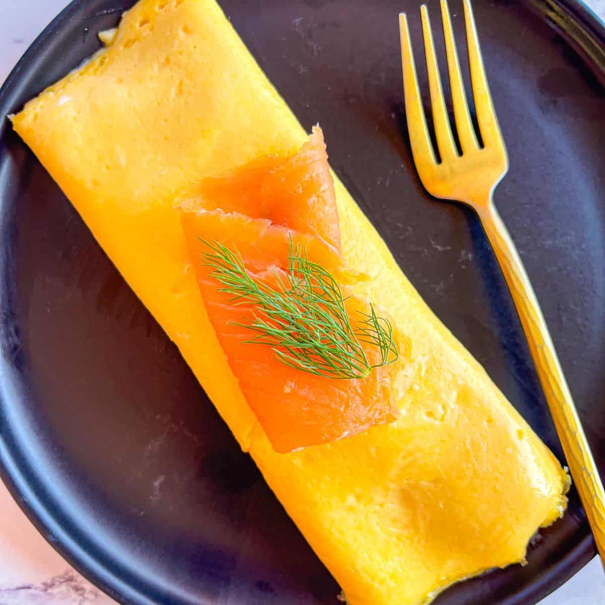 smoked salmon omellete on plate and served with a fork.