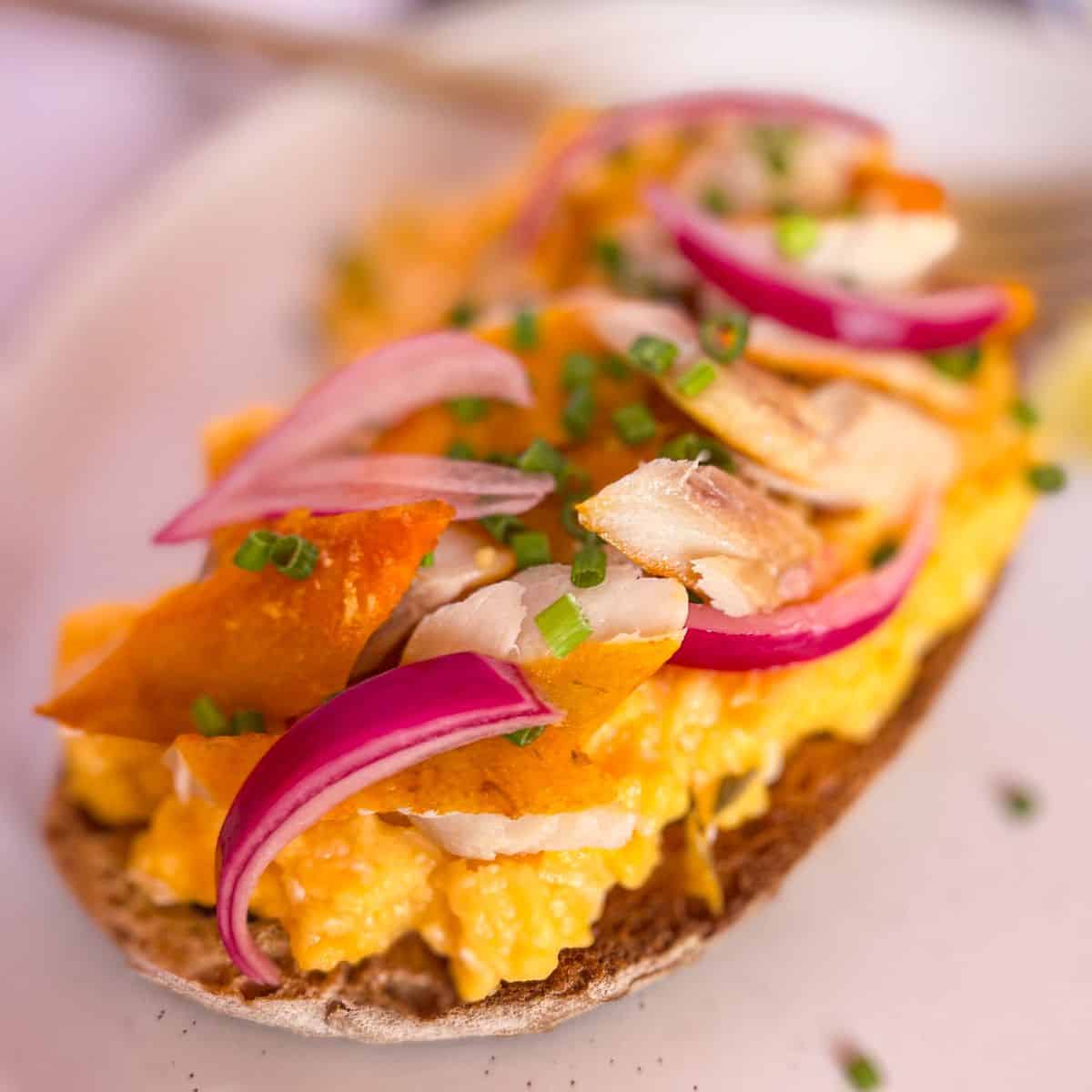 Kippers on scrambled eggs and toast garnished with pickled onions.