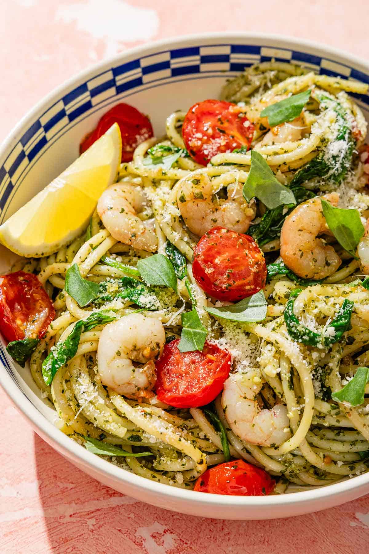 Une portion des pâtes au pesto de crevettes dans un bol avec un coin de citron.