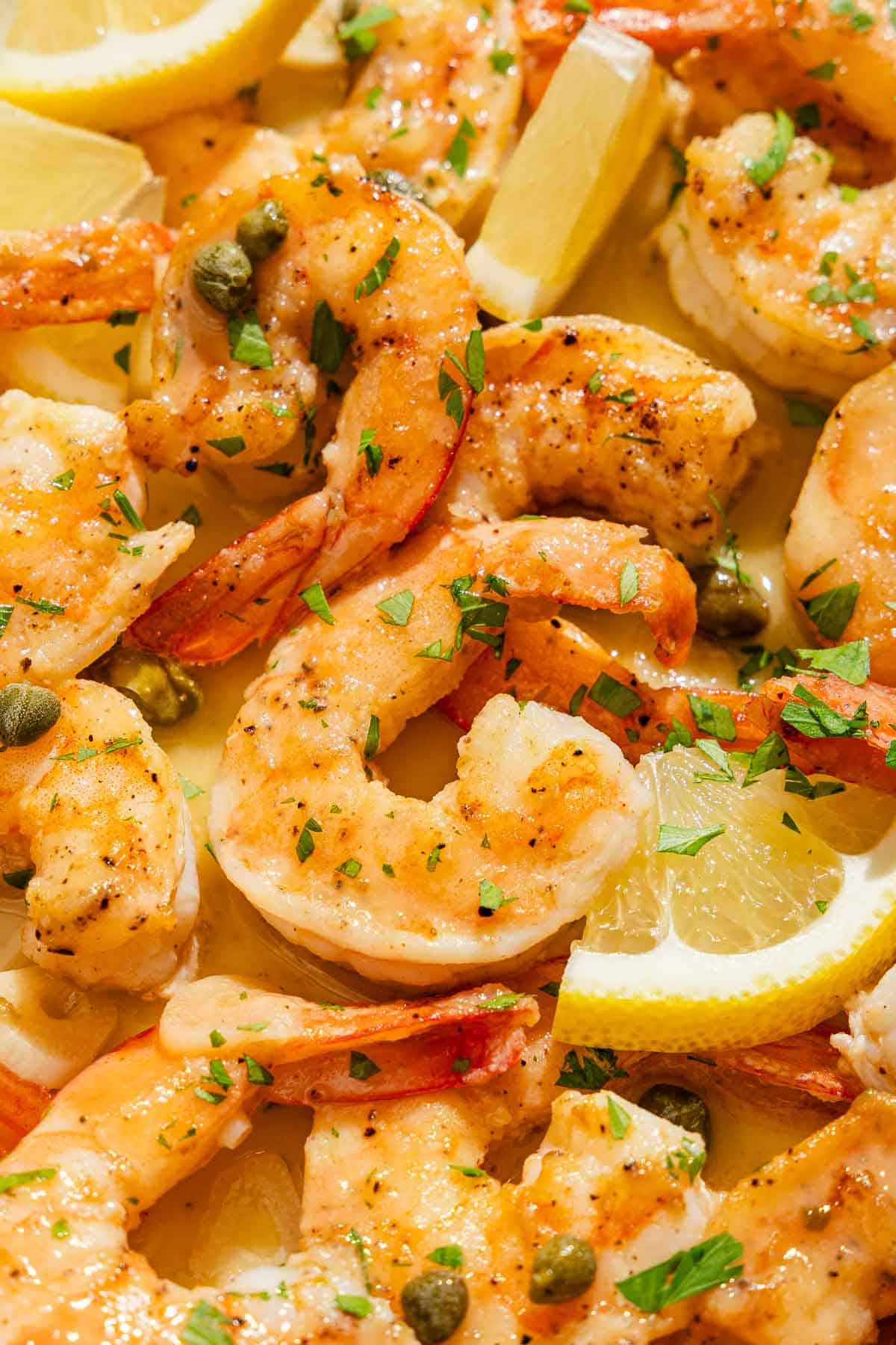 Un gros plan de piccata de crevettes avec des quartiers de citron.