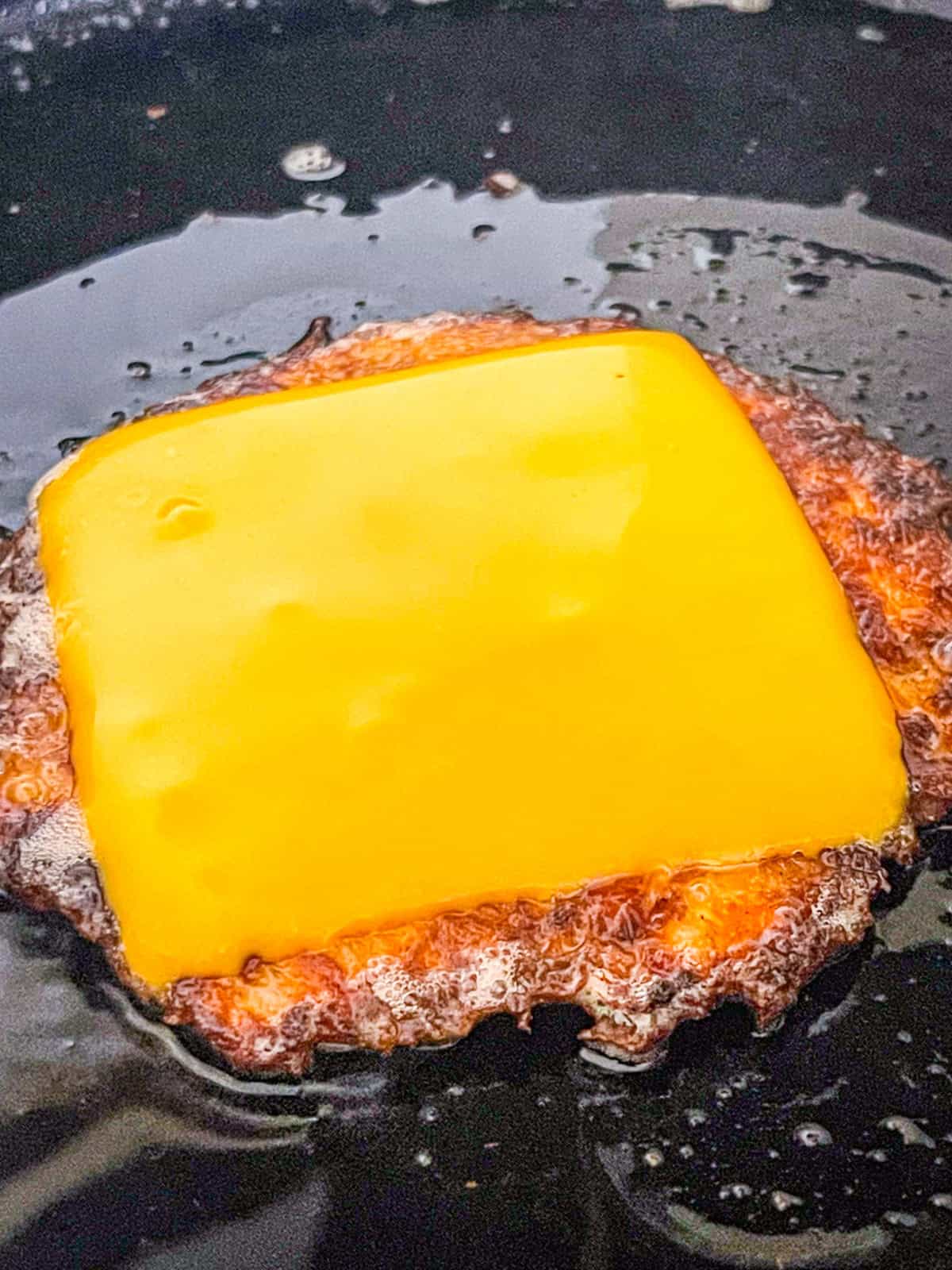 Burger de saumon avec fromage dans une poêle.