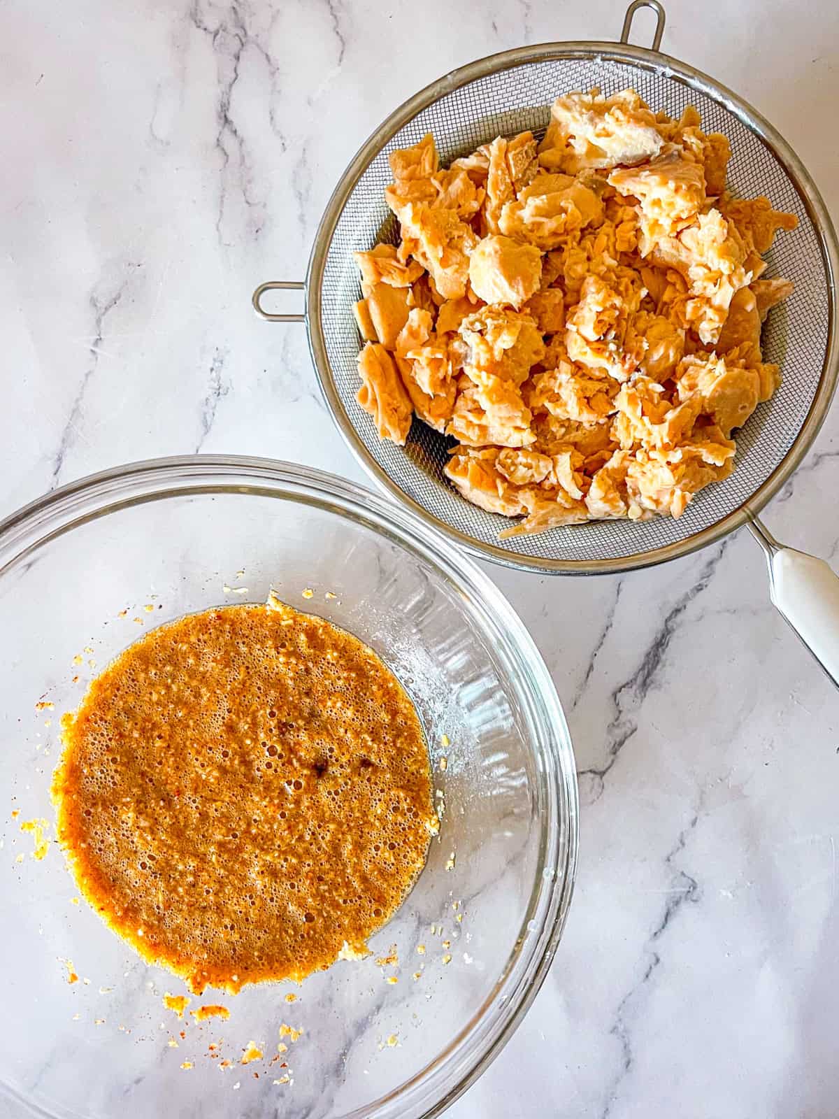 Panko, œufs et assaisonnements dans un bol à côté du saumon en conserve s'écoulant dans un tamis.