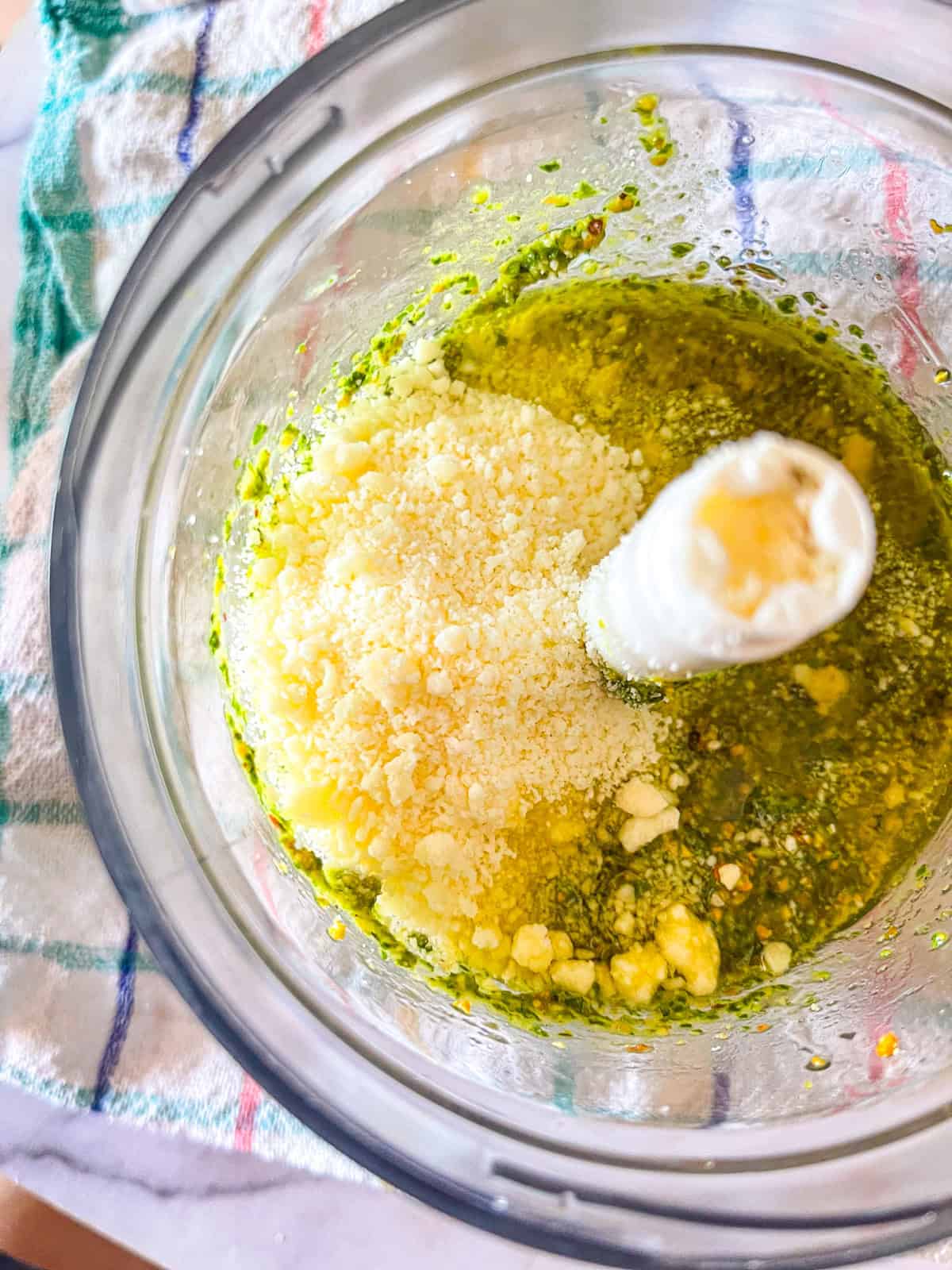 Le parmesan ajouté au mélange de pesto dans le processeur.