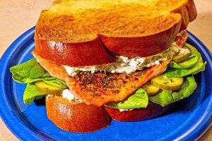 A close up of a salmon sandwich on a plate.