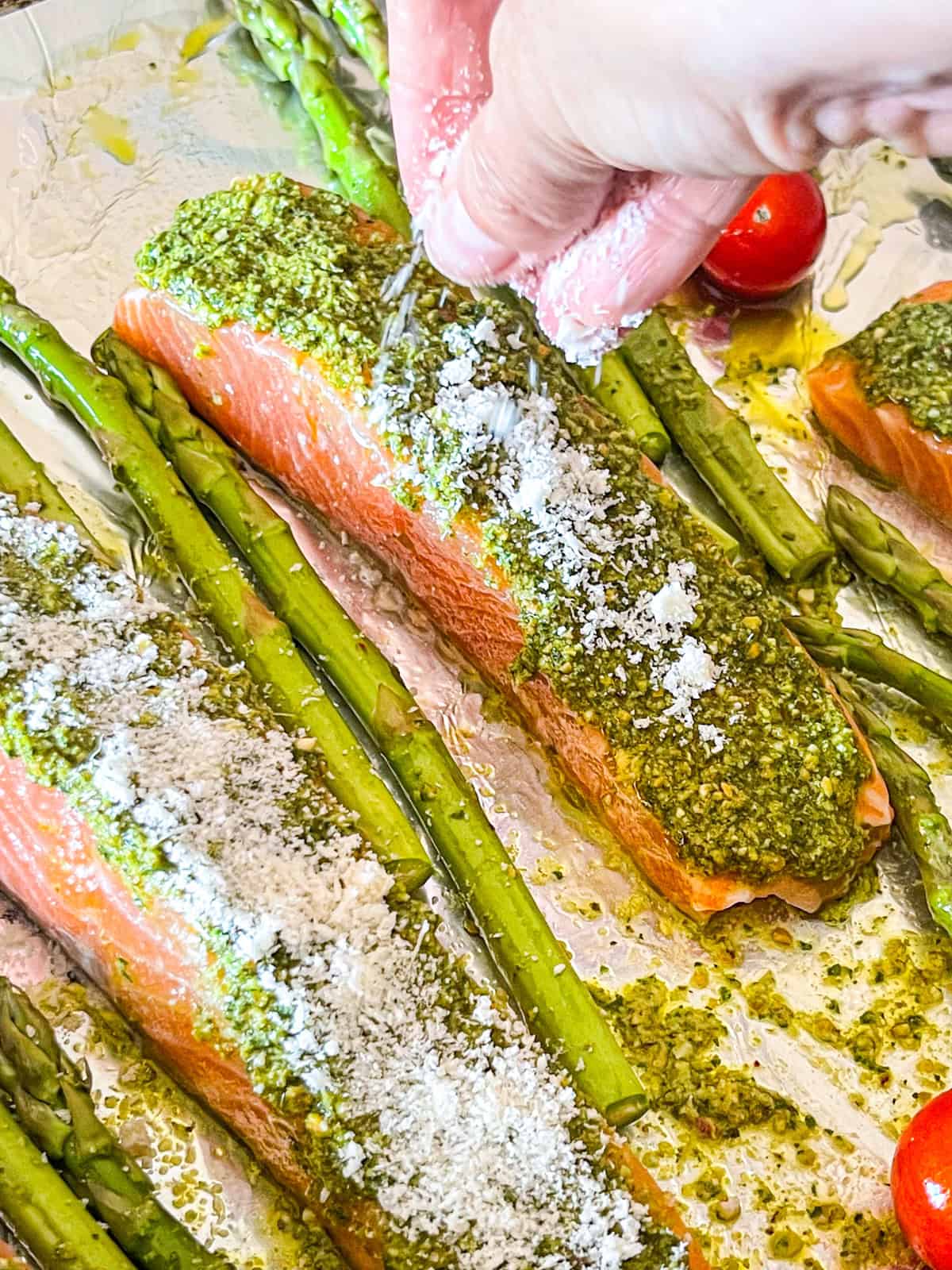 Sauprouiller le parmesan râpé sur les filets de saumon topped au pesto.