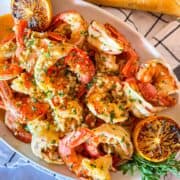 Plateau de scampi de crevettes sans vin garni de citron grillé et de persil coupé en dés.