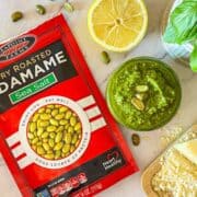 Edamame pesto sur une table avec du basilic, du parmesan et du citron.