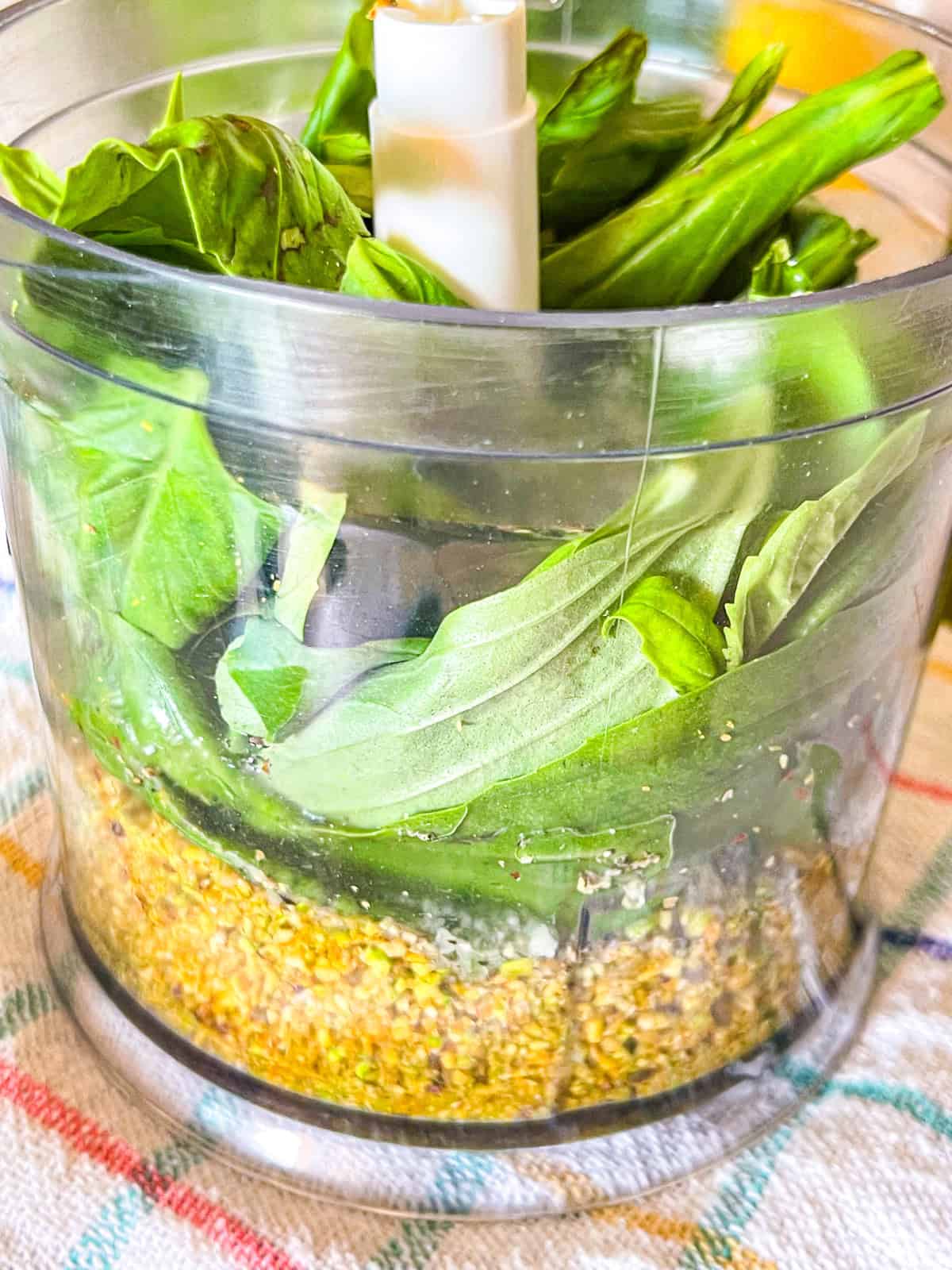 Basilic dans le robot culinaire avec des pistaches moulues. 