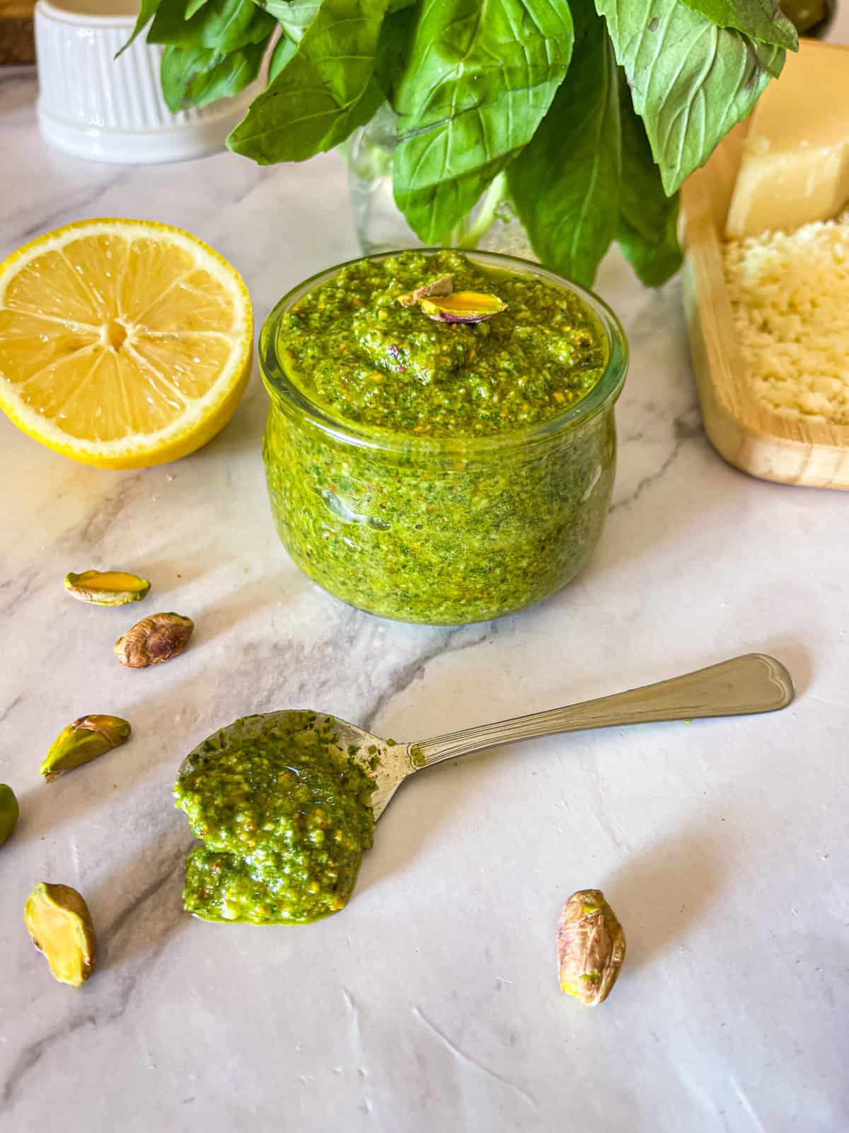 Pistache pesto dans un bocal en verre garni de noix grillées et de citrons. 