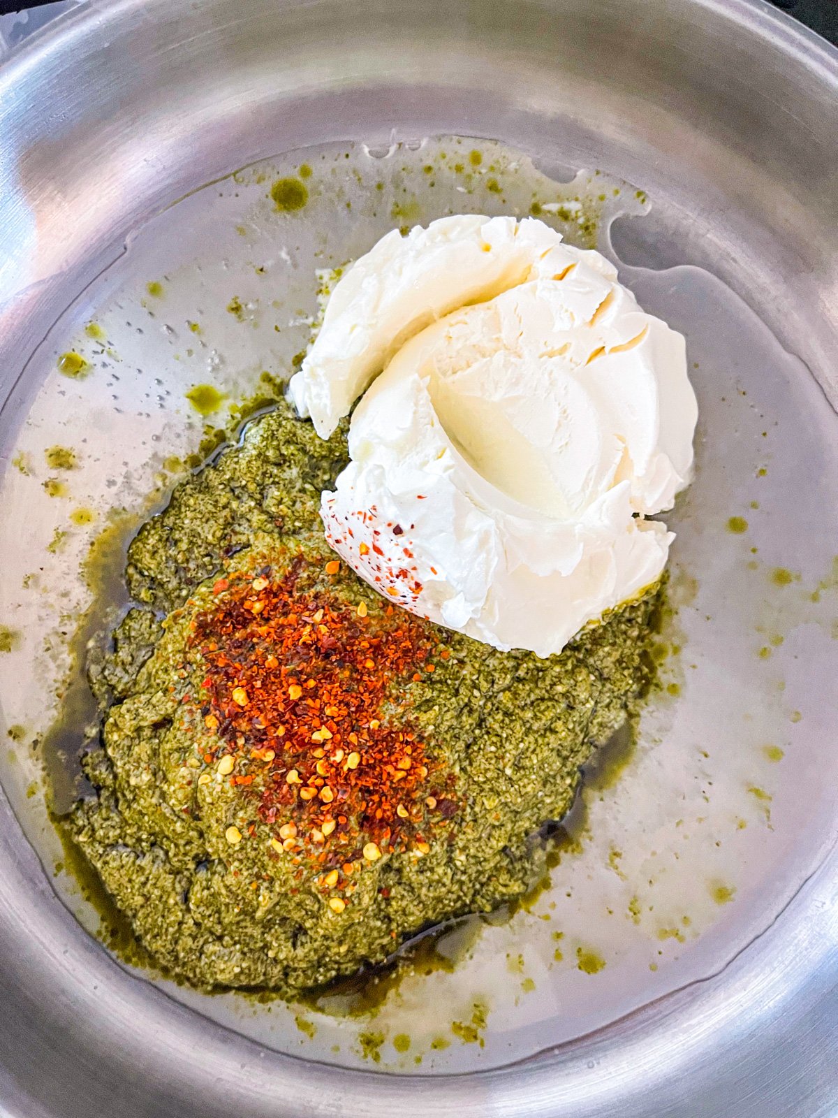 Ingrédients pour pâtes à pesto dans une poêle.