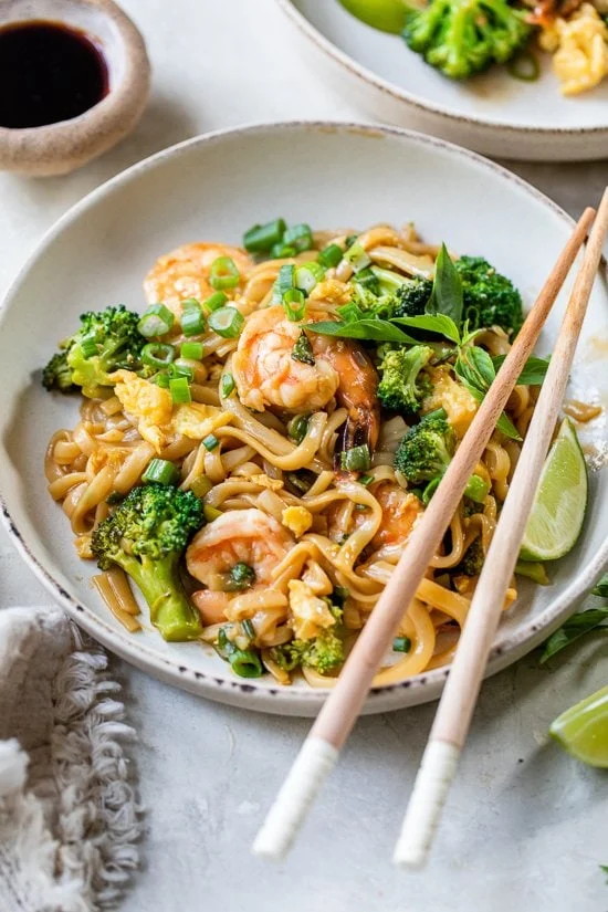 Nouilles ivres aux crevettes et baguettes sur une assiette.